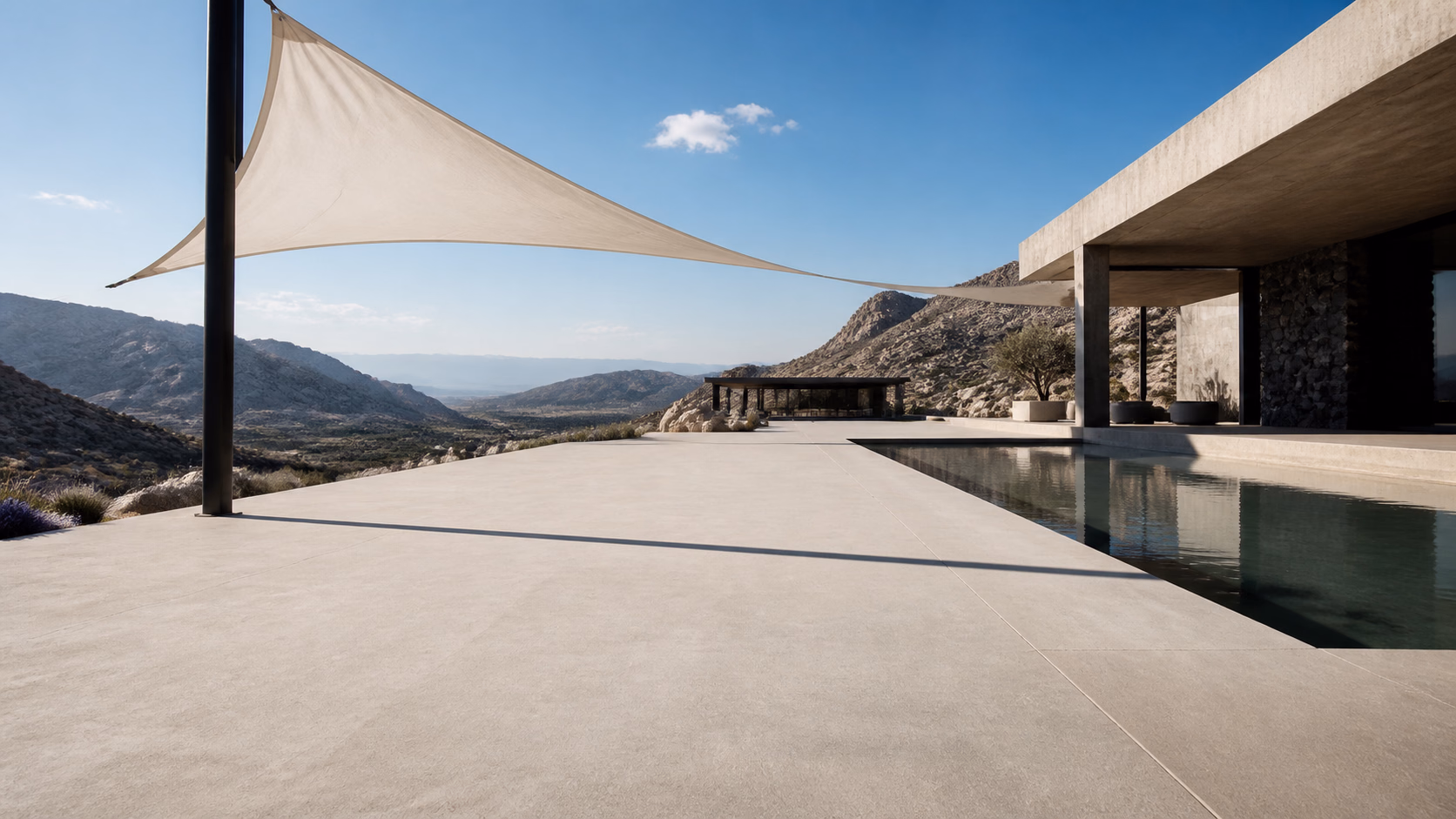 Pabellón de concreto con sombra textil y piscina frente a un valle montañoso